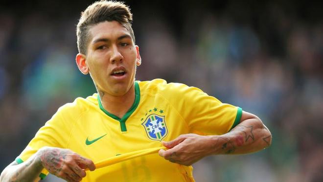 Roberto Firmino in the act of taking his shirt off after scoring for Brazil. 