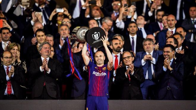 Andres Iniesta hoists the Copa del Rey trophy above his head in joy.